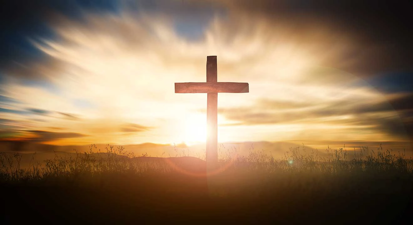 Sun rising behind the cross on a hill