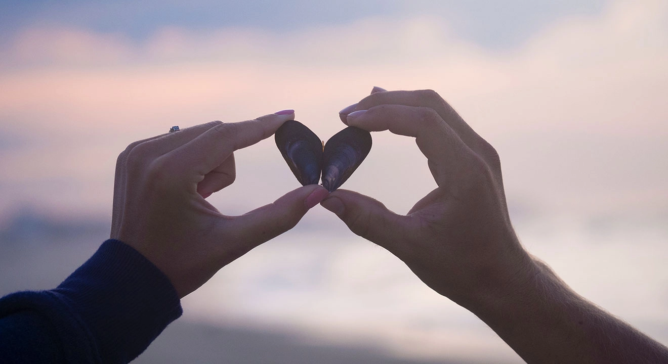 A woman holding 2 rocks in the shape of a heart