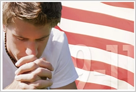 A young man praying in front of the American flag with the numbers 9-11