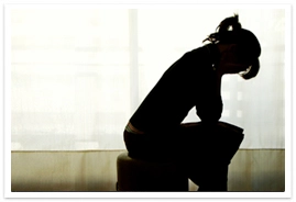Silhouette of a young lady sitting with her elbows on her knees