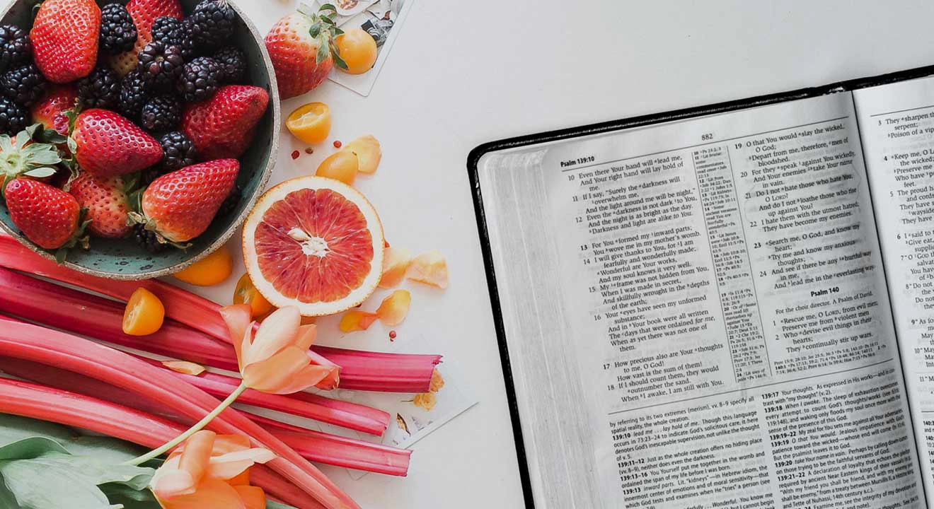 Fruits and vegetables on table with an open Bible
