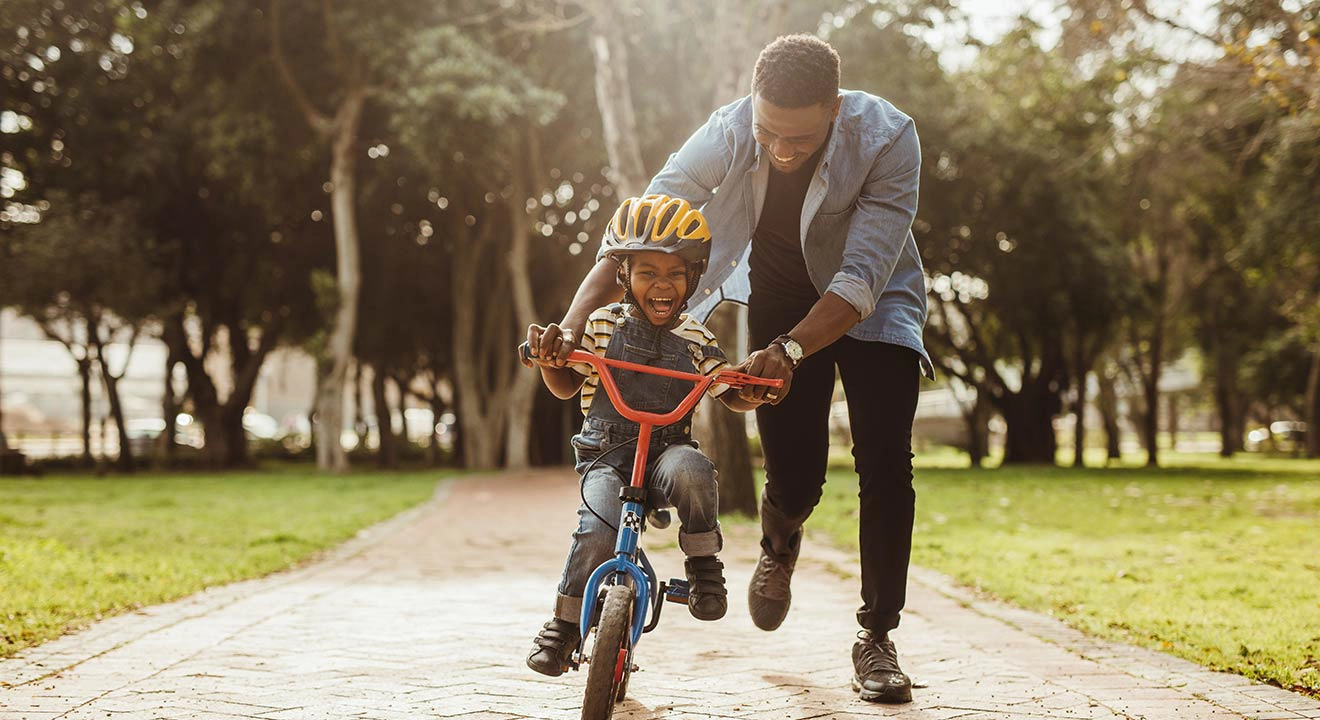 A father guiding his son to learn to ride a bicycle