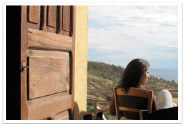 A young woman sitting on a chair outside of an open door