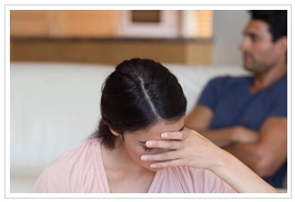 Women in foreground with her face in her hand with man in background