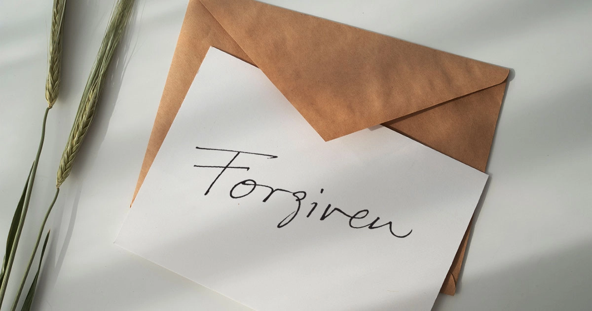A card with the word Forgiven written on it over an envelope