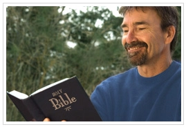 A man smiling while reading a Bible