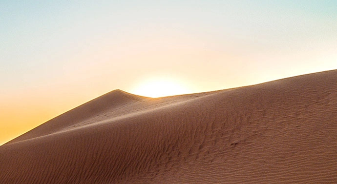 Sun rising over a sand dune