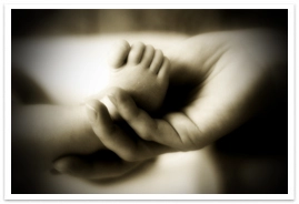 An adult's hand holding an infant's foot