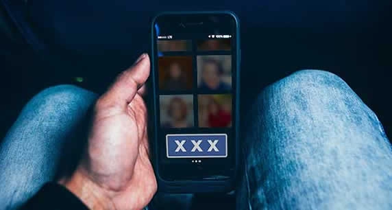 Man holding a phone with XXX on the screen