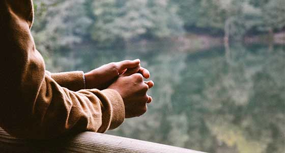 Man leaning elbows on a railing overlooking water