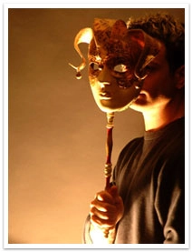 A person holding a mask on a stick in front of their face