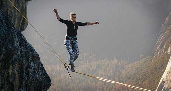A man walking a tightrope high above a valley