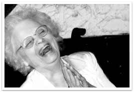 An elderly woman leaning back and laughing