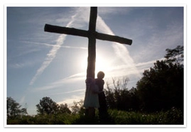 A person clinging to the cross in a meadow